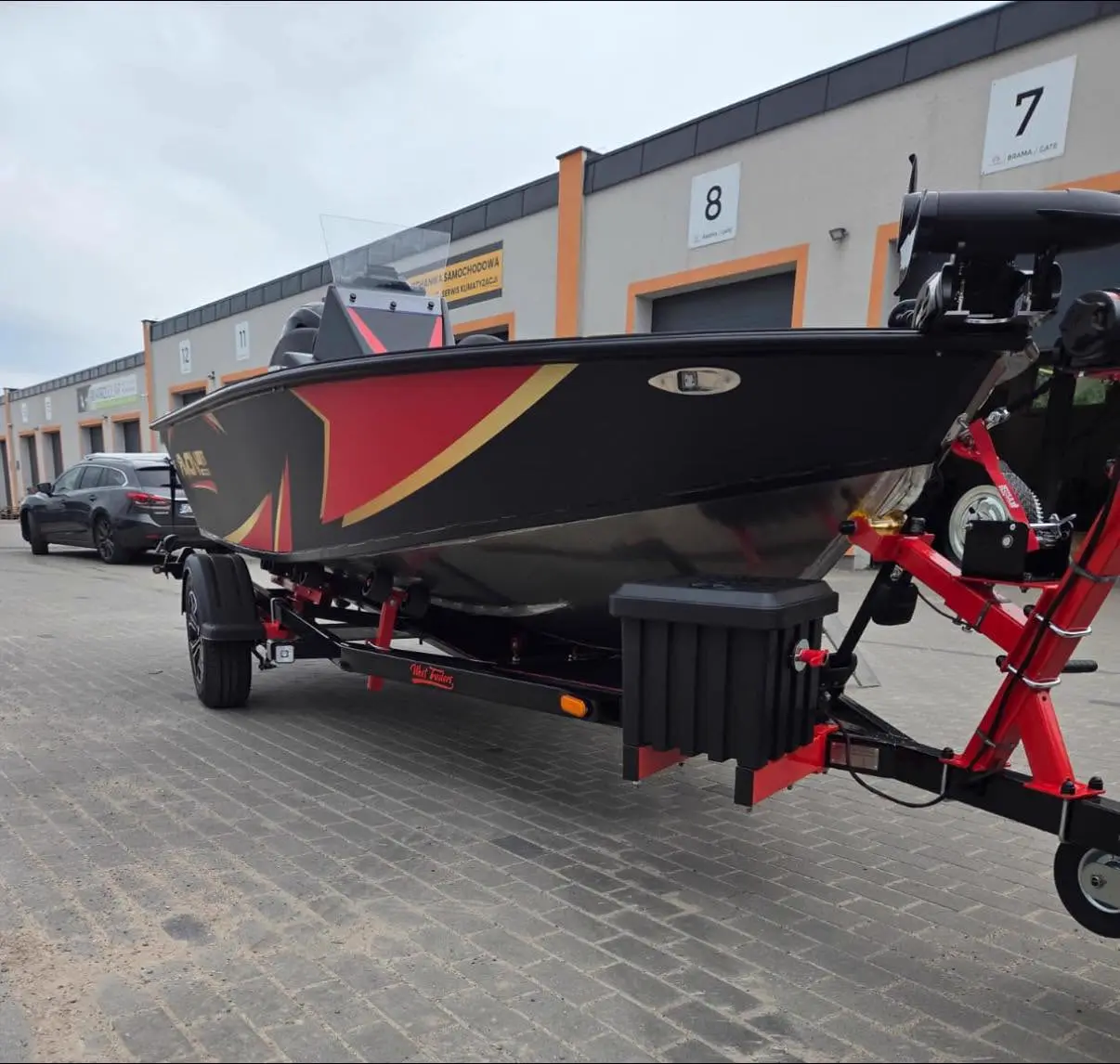 Łódź wędkarska na przyczepie West Trailers przed halą, widok od przodu